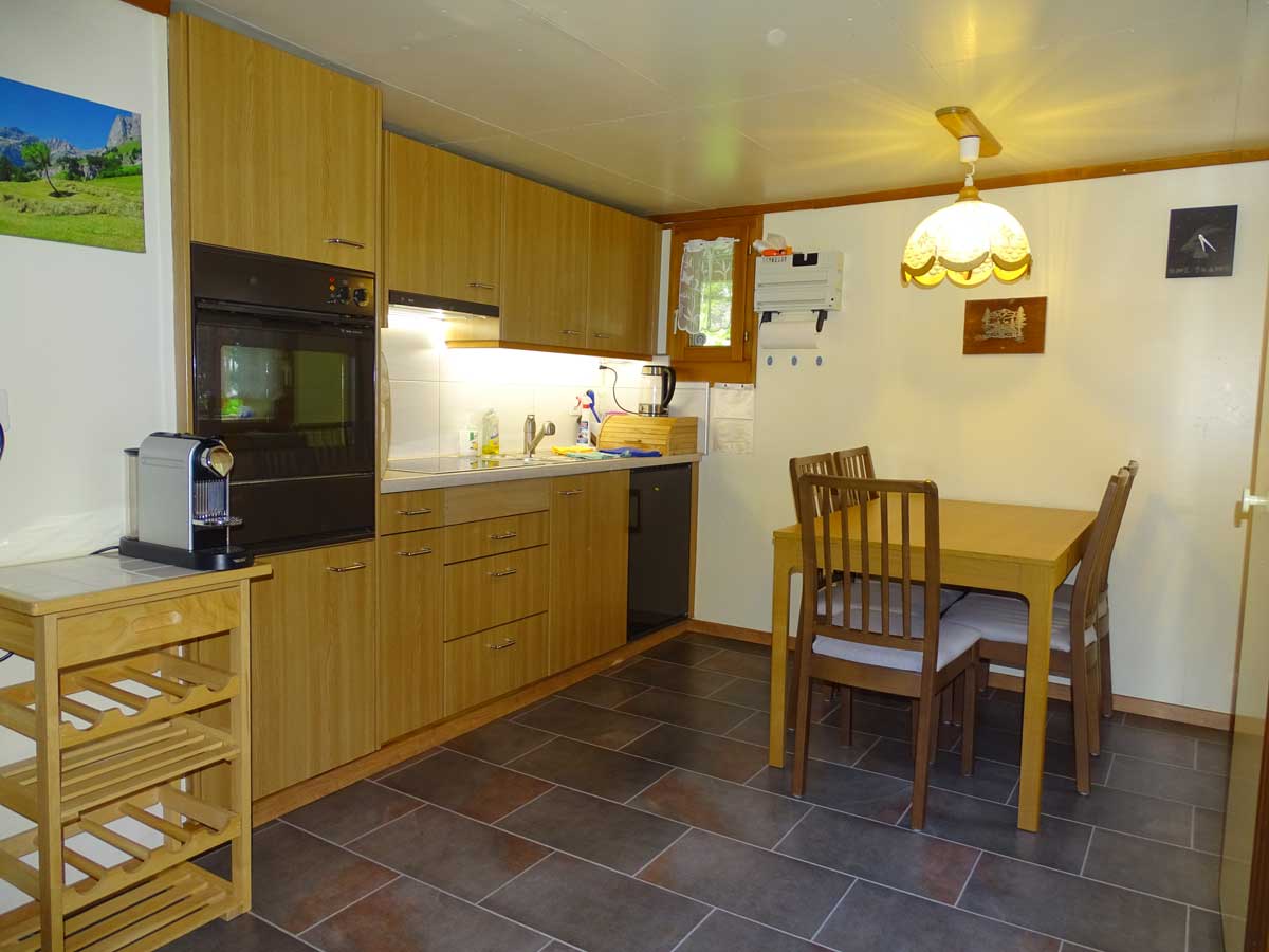 Photo de la cuisine de l'appartement à louer. Grande cuisine bien fournie, four, plaques à induction, machine à café, ustensiles de cuisine, épices. Et une grand table en bois avec des chaises confortables