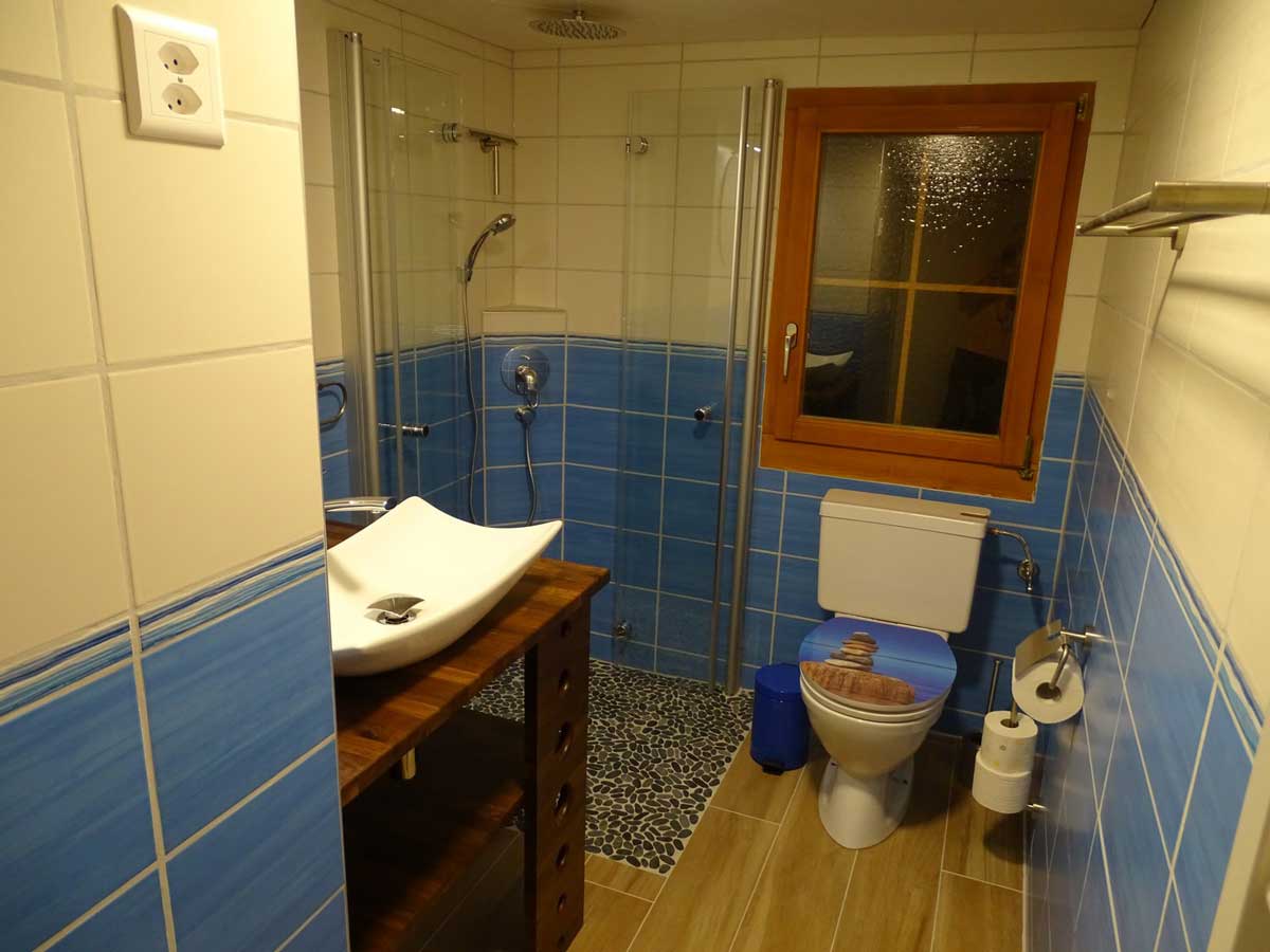 Photo de salle de bain de l'appartement à louer. Grande douche à l'italienne, grand lavabo et toilette. Meuble de rangement, et chauffage pour les linges