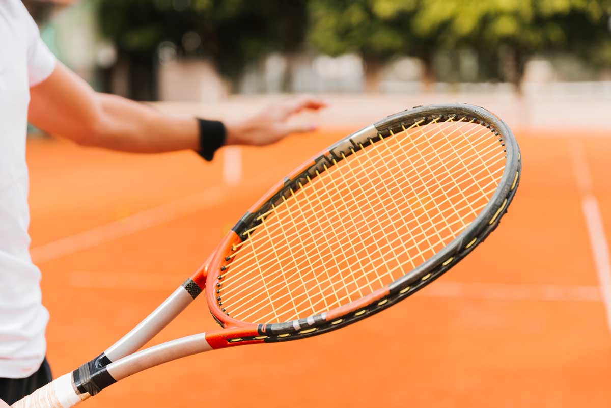 Joueuse de tennis tenant une raquette, sur un terrain de tennis orange